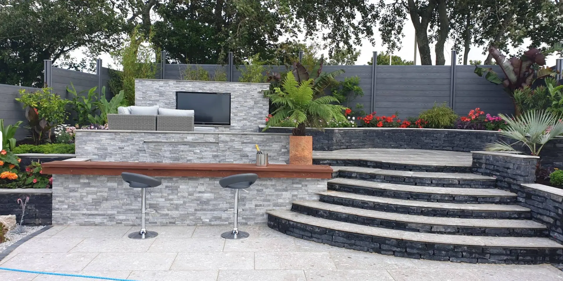 Finished outdoor entertaining area with bar, curved steps and architectural planting